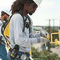 african american roofer attaching safety equipment 