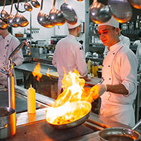 chef is cooking with open fire in a commercial kitchen