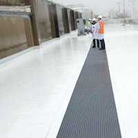 two manufacturing workers walking on a walk pad on the roof