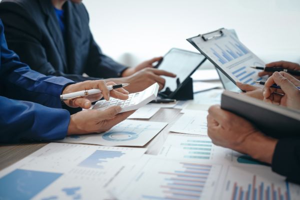 Group gathering at a table with spreadsheets and graphs